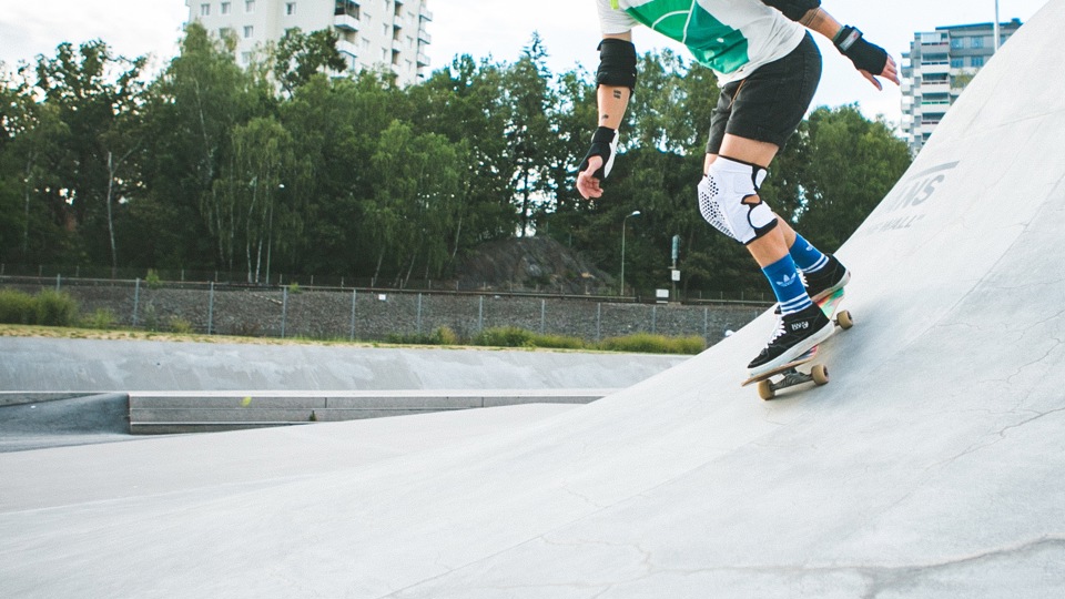 En person med knä- och handledsskydd åker skateboard i en skateramp.