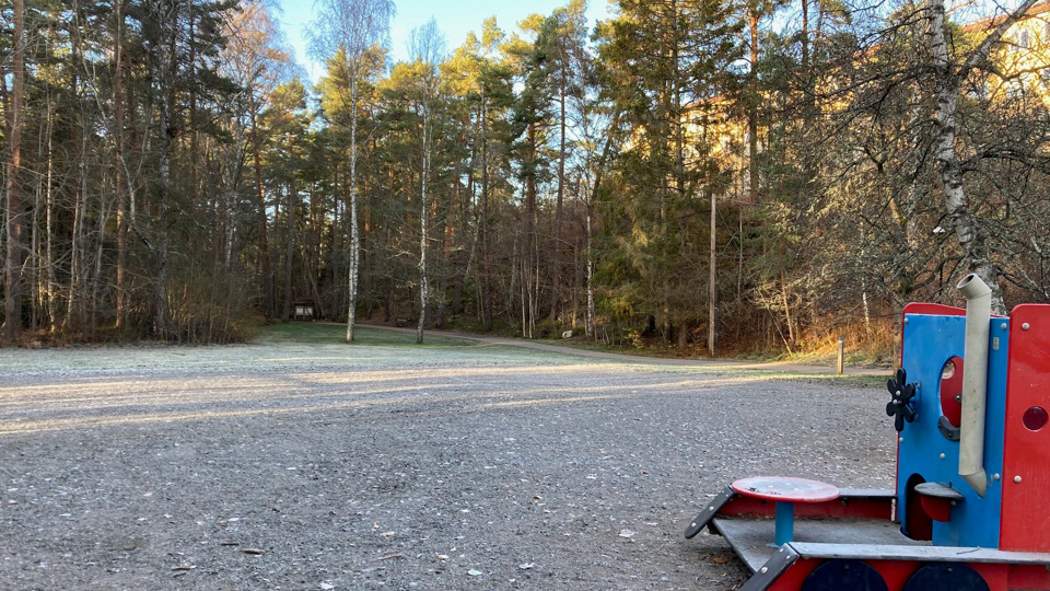 Bollplan intill en skog och en mindre lekplats.