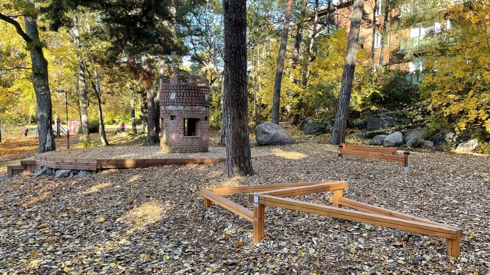 Parkmiljö med träredskap man kan balansera på samt en lekborg.