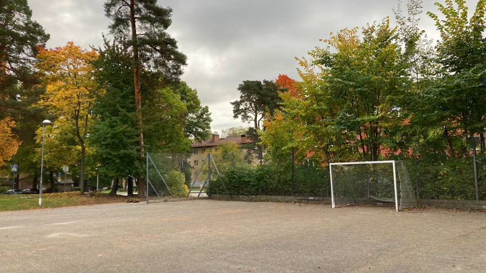 En stor grusplan med ett fotbollsmål och en gatlykta. Bakom målet finns ett högt gallerstaket.