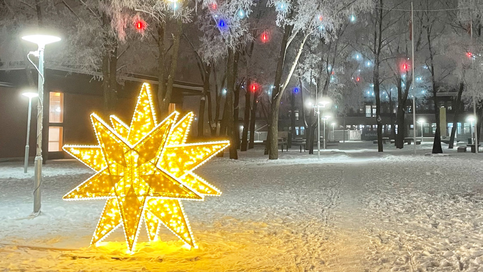 Snötäckt park med lysande stjärnskulptur, foto.