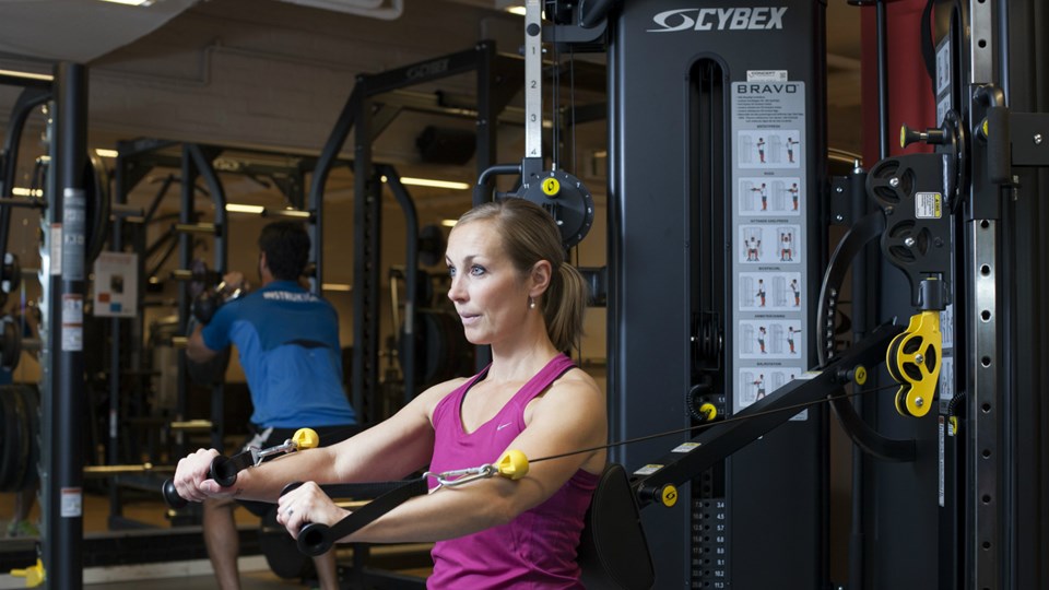 En kvinna som tränar i ett redskap i ett gym.