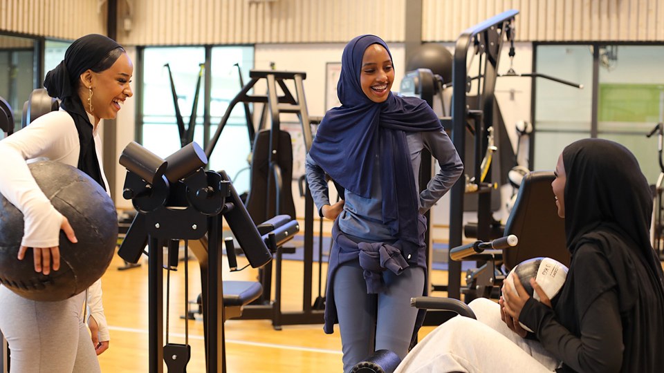 Tre tjejer som skrattar åt något i ett gym.