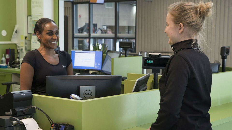 En besökare som pratar med en person som står i en reception.