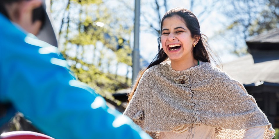 En ung kvinna som skrattar under en aktivitet i en park.