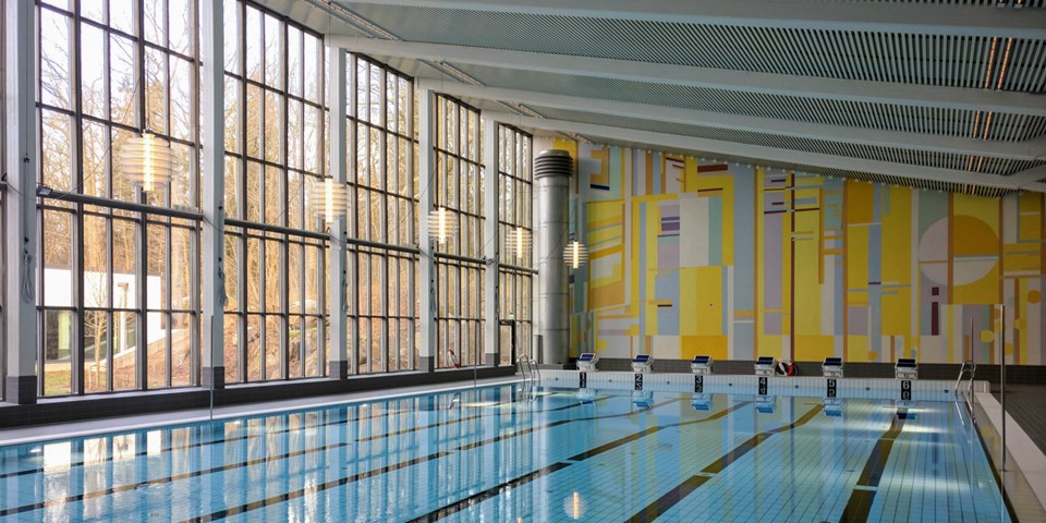 En interiörbild av Åkeshovs simhalls äldre simbassäng med en väggmålning från när byggnaden uppfördes.