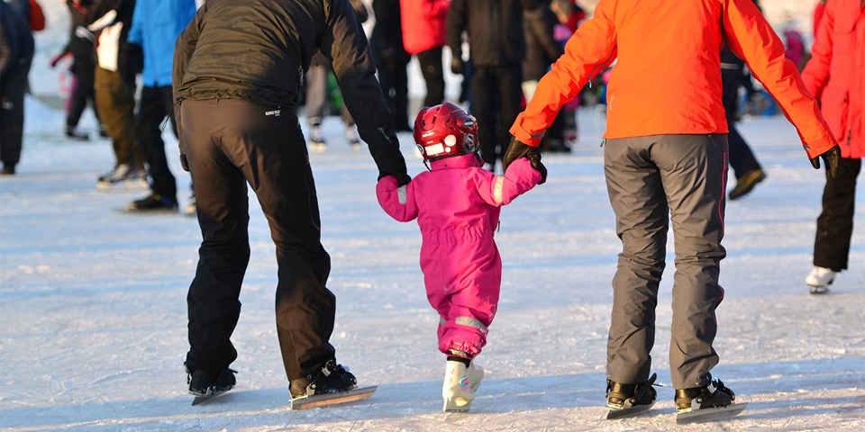 Barn och vuxna som åker skridsko på en solig isbana. Foto Petra Sundström .
