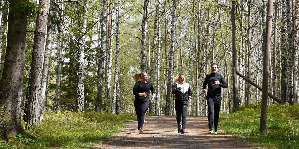Tre personer som joggar tillsammans på ett motionsspår i skogen.