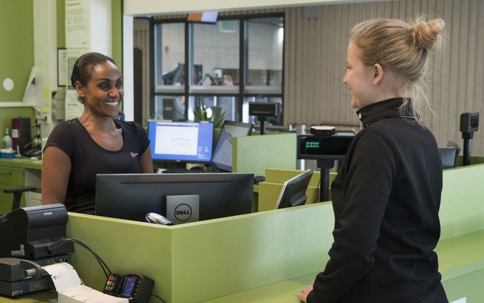 En besökare som pratar med en person som står i en reception.