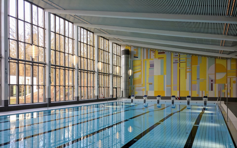 En interiörbild av Åkeshovs simhalls äldre simbassäng med en väggmålning från när byggnaden uppfördes.