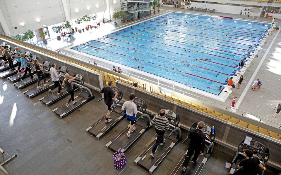 En översiktsbild med personer som springer på löpband och med Eriksdalsbadets stora bassäng i bakgrunden.