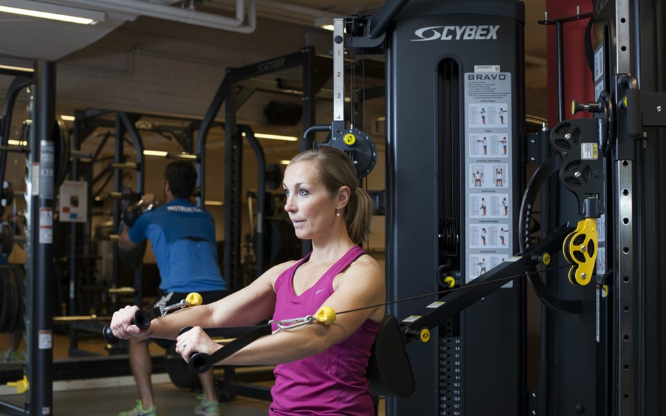 En kvinna som tränar i ett redskap i ett gym.