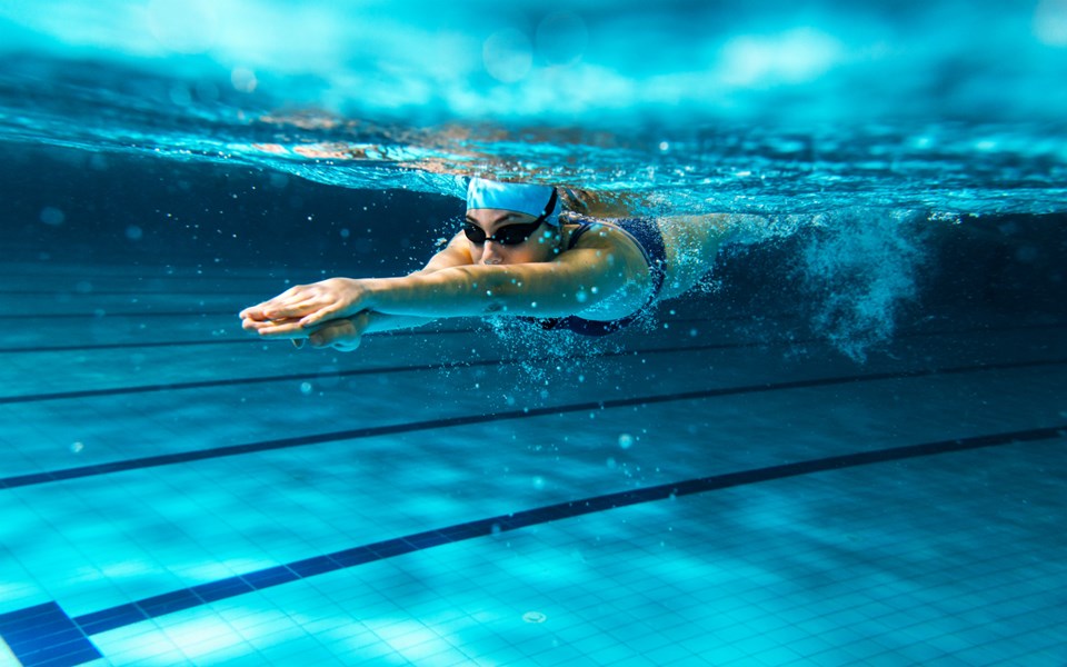 En undervattensbild på en kvinna som simmar under vattnet.