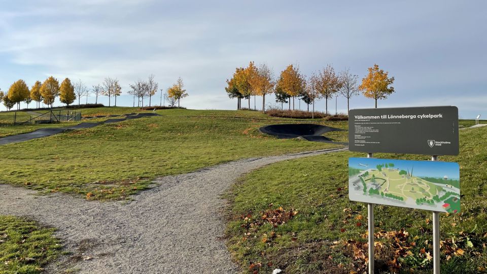 Cykelbana på slänt med öppna grönytor och träd i bakgrunden