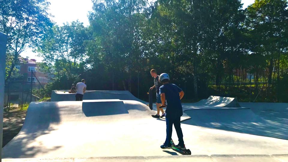 Ungdomar åker skateboard och kickbike i en skatepark.