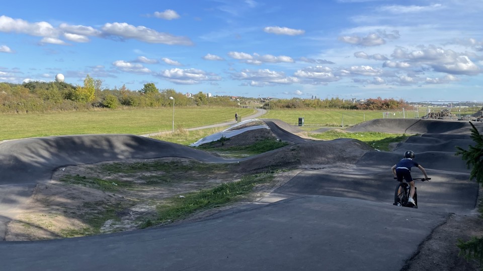 En pojke cyklar på en asfalterad bana som slingrar slig upp och ned för små kullar.